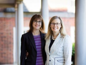 Two adoption attorneys pose together for a photo next to a North Carolina family law court.